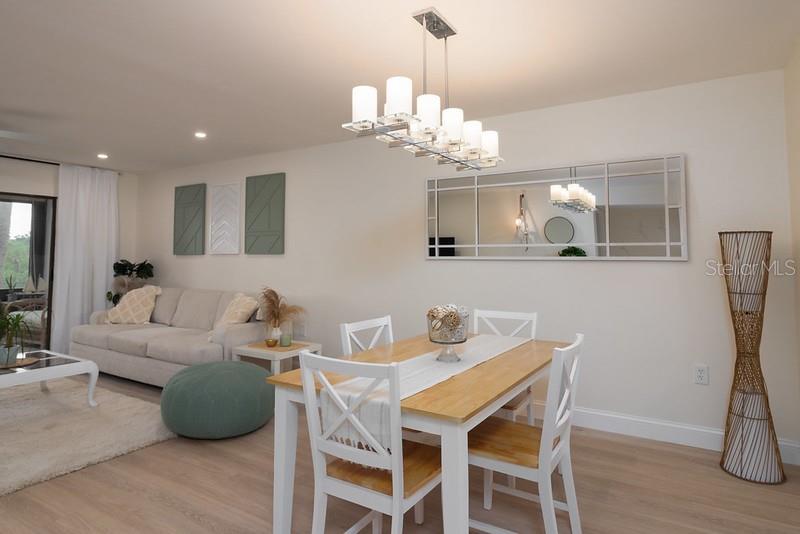 A dining area with a wooden table and chandelier sits adjacent to a living room — 223 LAKEWOOD DRIVE UNIT 223, BRADENTON, FL