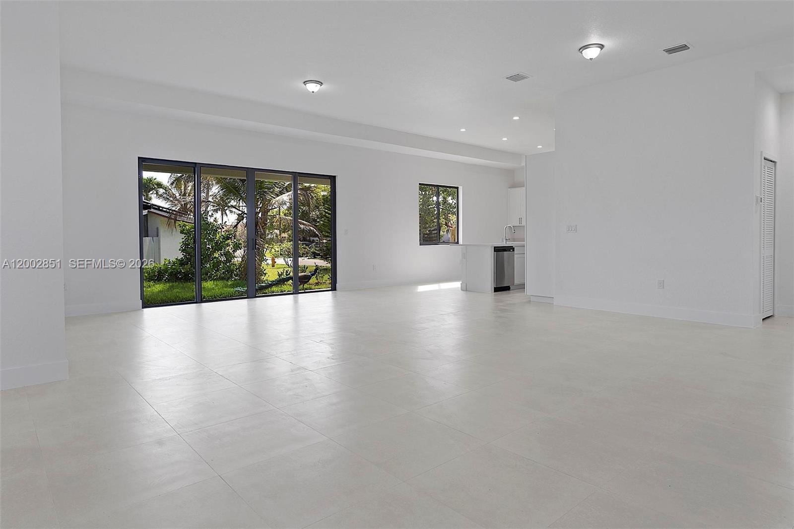 An open-concept living area features white tile flooring, recessed lighting, and large sliding glass doors — 20943 SW 96th Ct, Cutler Bay FL 33189, CUTLER BAY, FL