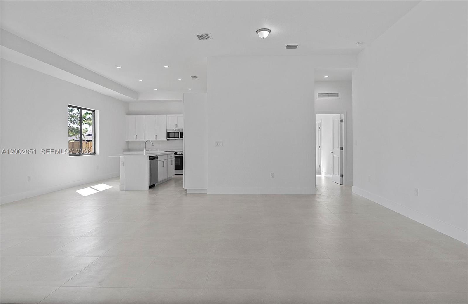 A bright, open-concept kitchen and living area features white cabinetry, tile flooring, and recessed lighting — 20943 SW 96th Ct, Cutler Bay FL 33189, CUTLER BAY, FL