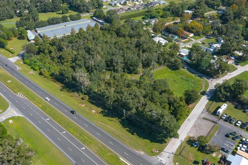 An aerial view shows a wooded lot situated between a multi-lane highway and a residential area — N US HWY 441, OCALA, FL