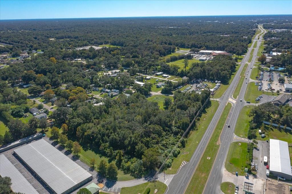 An aerial view shows a wooded lot adjacent to a highway and commercial buildings — N US HWY 441, OCALA, FL