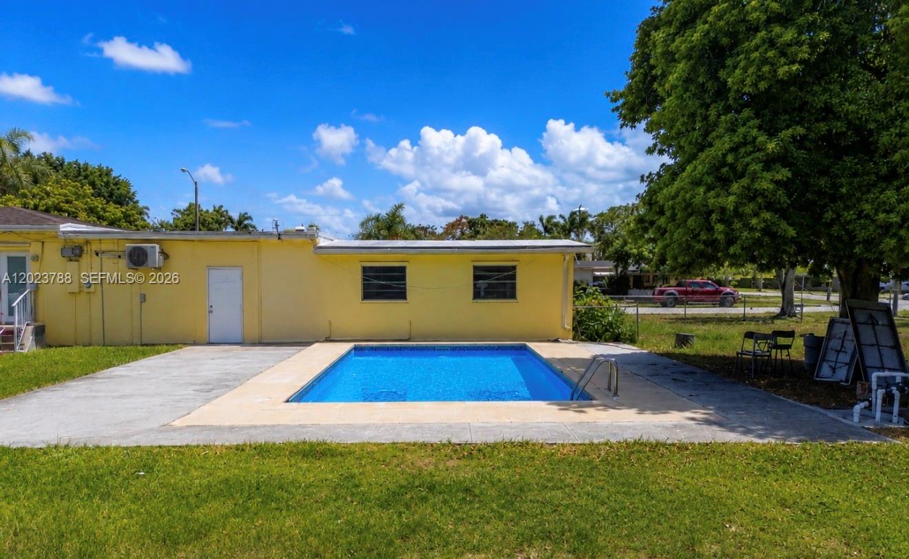 A yellow house exterior features a rectangular swimming pool and a concrete patio area — 329 NW 13th St, Homestead FL 33030, HOMESTEAD, FL