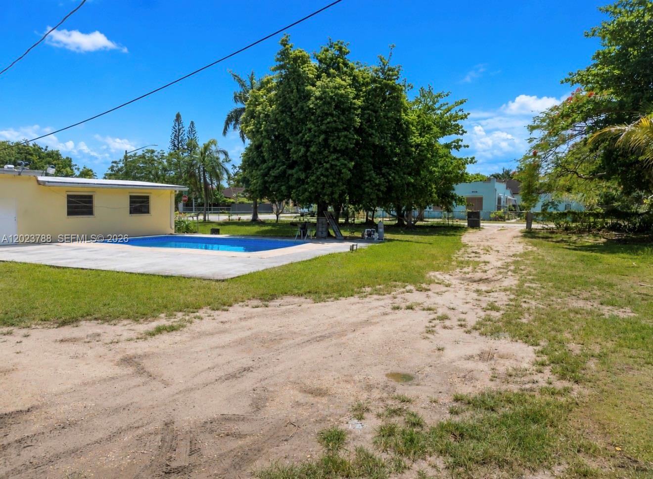 A backyard features a swimming pool, a concrete patio, and a large tree — 329 NW 13th St, Homestead FL 33030, HOMESTEAD, FL