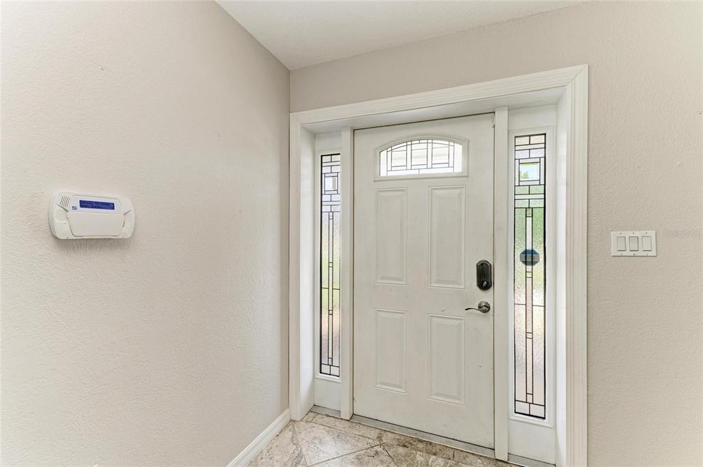 An entryway features a white front door with sidelights, a security panel, and tiled flooring — 557 READING STREET NW, PORT CHARLOTTE, FL