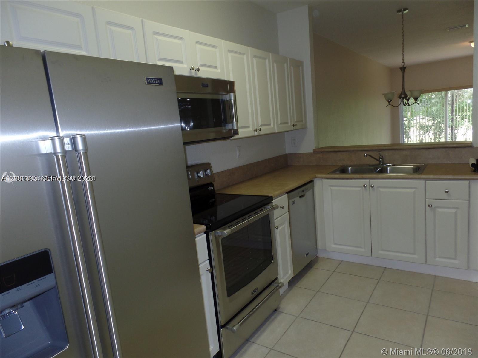 A kitchen features white cabinets, stainless steel appliances, and a double sink with tile flooring — 14055 SW 49th St # 6, Miramar FL 33027, MIRAMAR, FL