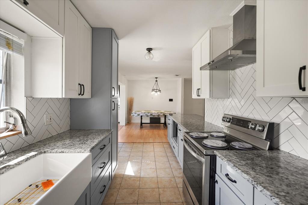 A kitchen with white upper cabinets, grey lower cabinets, granite countertops, and a herringbone backsplash — 814 DENSMORE DR, WINTER PARK, FL