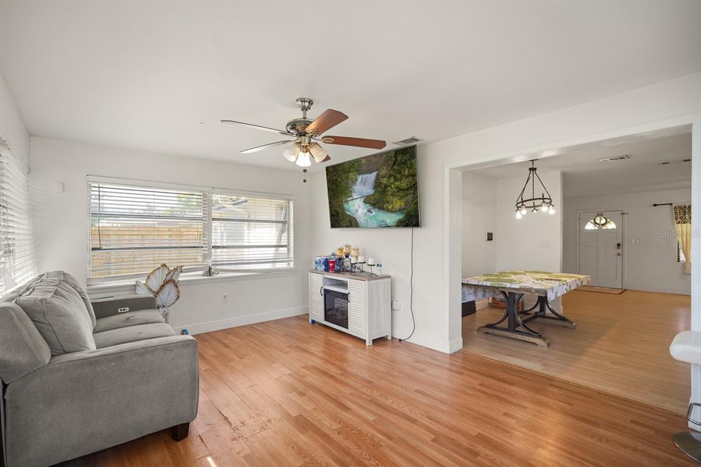 A living room with wood flooring, a gray sofa, a ceiling fan, and a television — 814 DENSMORE DR, WINTER PARK, FL