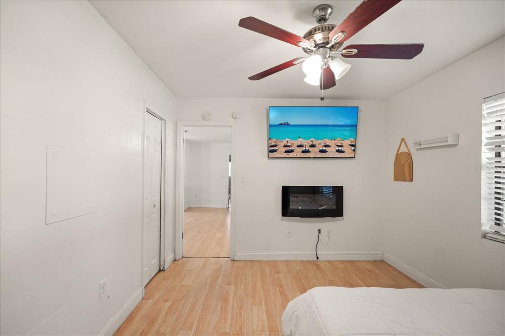 A bedroom features light wood flooring, a ceiling fan, a wall-mounted television, and an electric fireplace — 814 DENSMORE DR, WINTER PARK, FL
