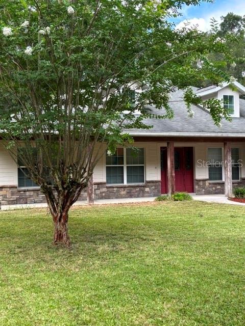 A single-story house with a gray roof, tan siding, and a large tree in front — 9209 MCINTYRE ROAD, BROOKSVILLE, FL