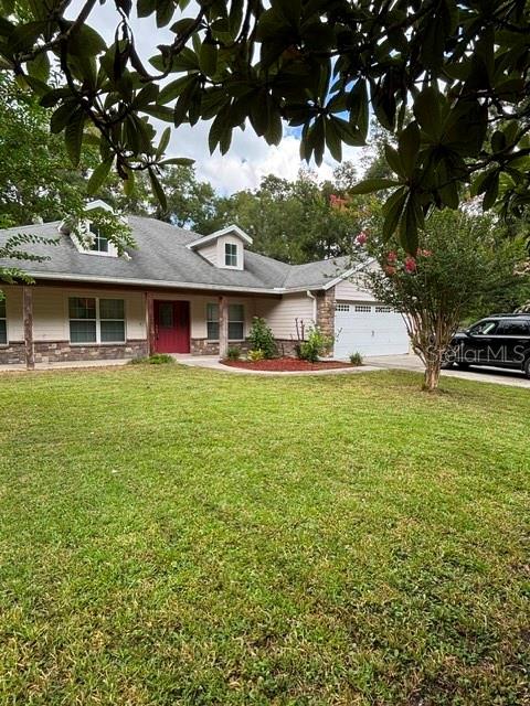 A single-story house with a gray roof, tan siding, and a red front door — 9209 MCINTYRE ROAD, BROOKSVILLE, FL