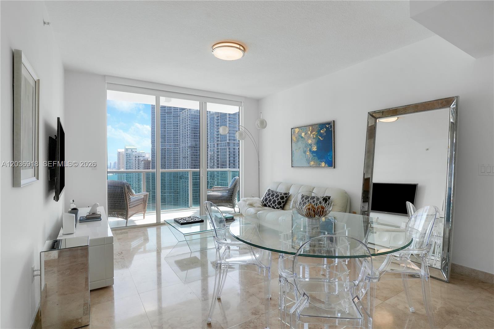 A modern living and dining area features glass furniture, a white sofa, and balcony views — 31 SE 5th St # 3812, Miami FL 33131, MIAMI, FL