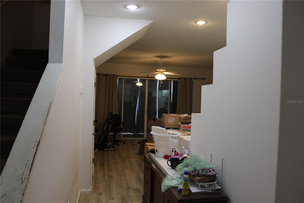 A view from a hallway looking into a living area with wood-look flooring and stairs — 202 HEMINGWAY DRIVE, OLDSMAR, FL