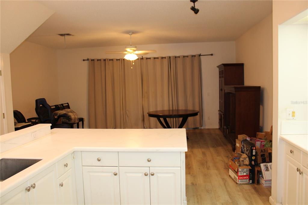 A kitchen island with white cabinets faces a dining area with a table and curtains — 202 HEMINGWAY DRIVE, OLDSMAR, FL