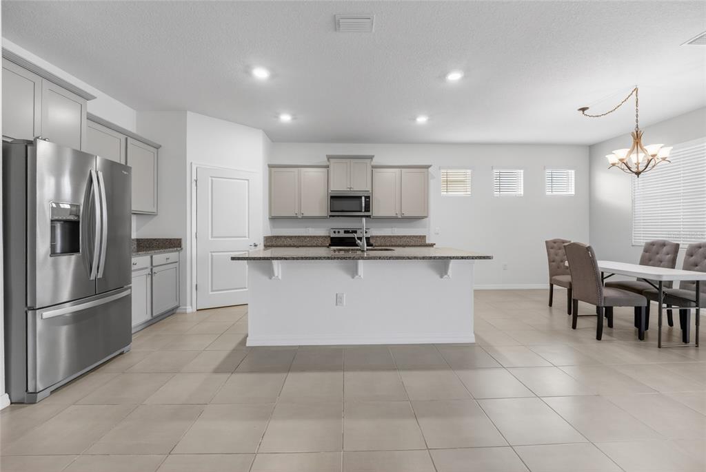 A kitchen features gray cabinets, stainless steel appliances, a central island, and an adjacent dining area — 8872 SW 63RD AVENUE, OCALA, FL