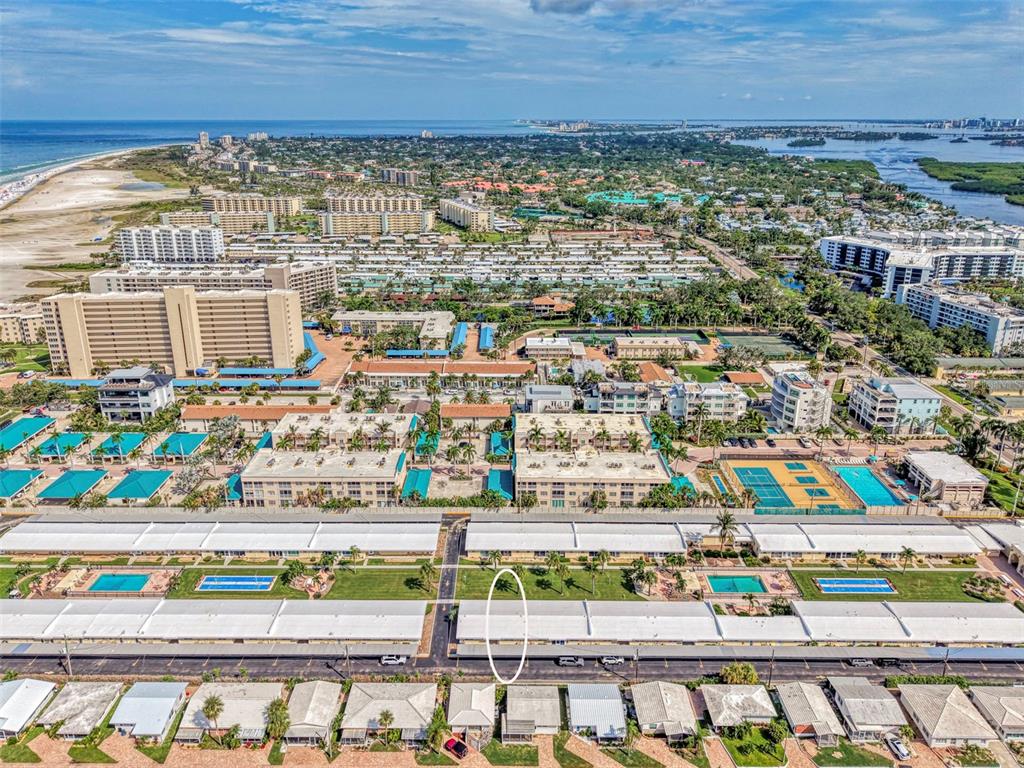 An aerial view shows a residential complex with swimming pools, parking structures, and nearby beaches — 6006 MIDNIGHT PASS ROAD UNIT 60, SARASOTA, FL