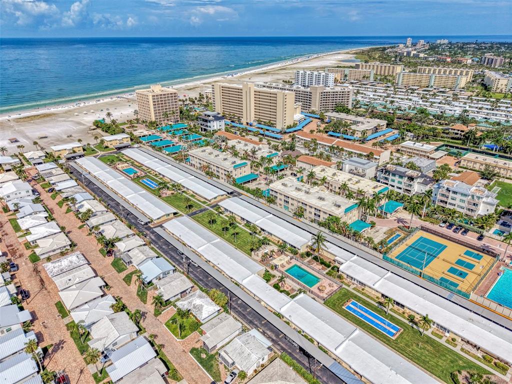 An aerial view shows a coastal resort with multiple buildings, swimming pools, and tennis courts — 6006 MIDNIGHT PASS ROAD UNIT 60, SARASOTA, FL