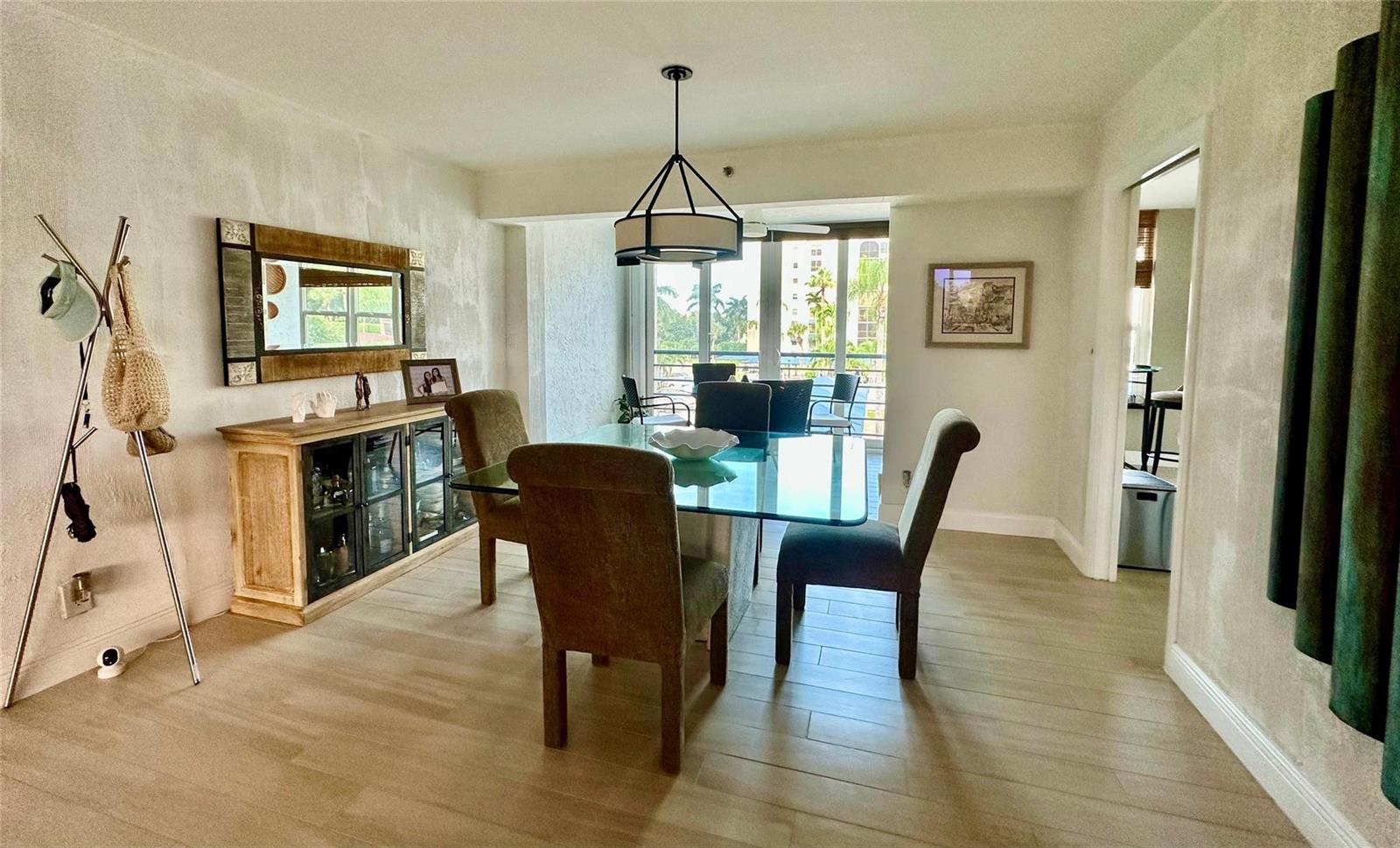 A dining room features a glass-topped table, upholstered chairs, a wooden sideboard, and balcony access — 7582 Regency Lake Drive, Boca Raton FL 33433, BOCA RATON, FL