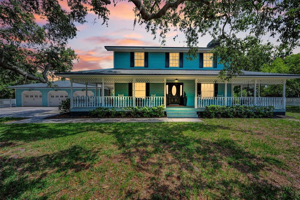 A two-story teal house with a wrap-around porch and an attached three-car garage — 3525 FAIRVIEW STREET, SAFETY HARBOR, FL