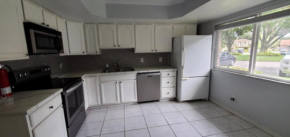 A kitchen with white cabinets, stainless steel appliances, a tiled backsplash, and a large window — 406 OAK HAVEN DRIVE UNIT 406, ALTAMONTE SPRINGS, FL