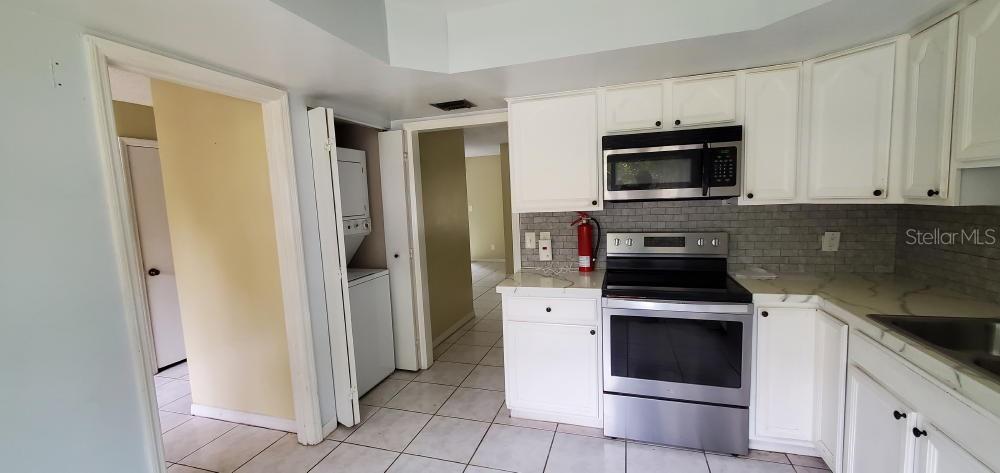 A kitchen with white cabinets, stainless steel appliances, a gray tile backsplash, and tiled floors — 406 OAK HAVEN DRIVE UNIT 406, ALTAMONTE SPRINGS, FL