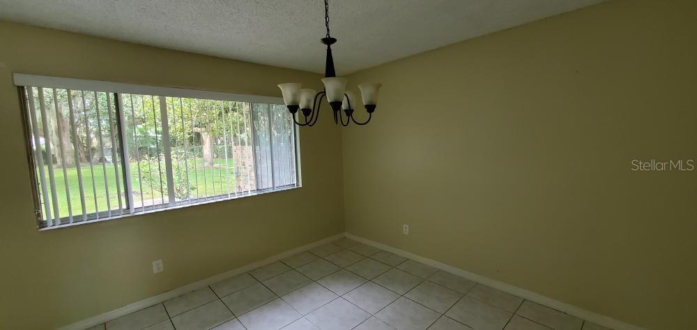 A dining room with beige walls, tile flooring, a chandelier, and a large window — 406 OAK HAVEN DRIVE UNIT 406, ALTAMONTE SPRINGS, FL