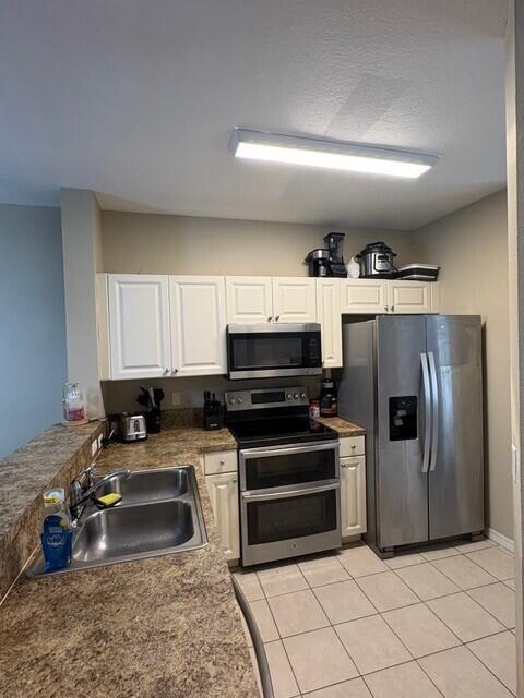 A kitchen features white cabinets, stainless steel appliances, and brown speckled laminate countertops — 1966 Alamanda Way, Riviera Beach FL 33404, RIVIERA BEACH, FL
