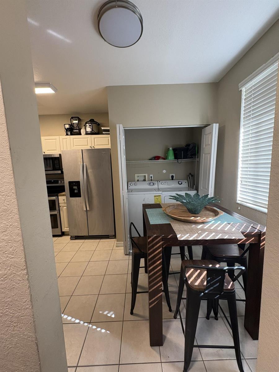 A dining area with a table and chairs sits adjacent to a kitchen and laundry closet — 1966 Alamanda Way, Riviera Beach FL 33404, RIVIERA BEACH, FL