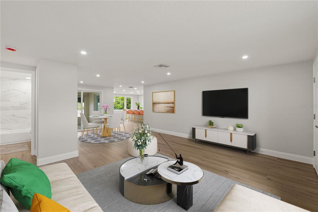 A modern kitchen features white cabinetry, a marble-topped island with orange stools, and wood flooring — 6617 HARBOR DRIVE, HUDSON, FL