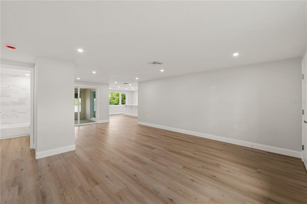 This living room features light wood flooring, a wall-mounted television, and an adjacent dining area — 6617 HARBOR DRIVE, HUDSON, FL