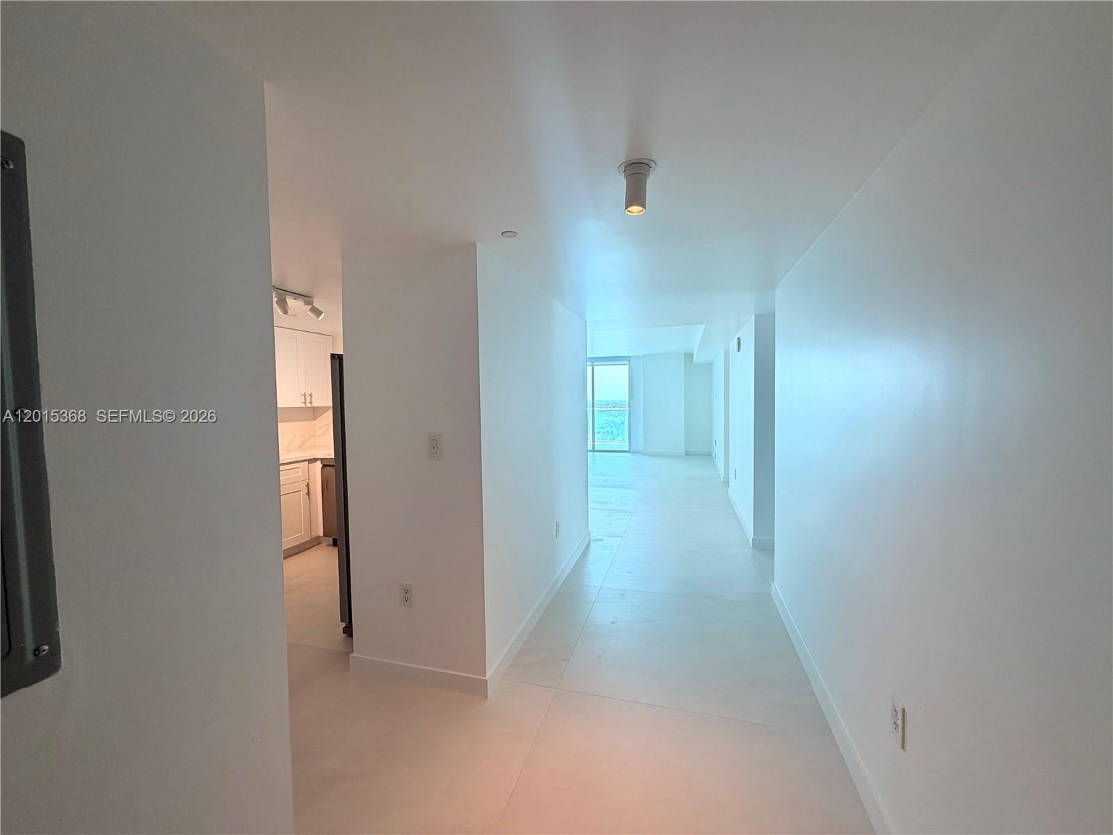 A bright hallway with white walls and tile flooring leads toward a distant windowed room — 2101 Brickell Ave # 2301, Miami FL 33129, MIAMI, FL
