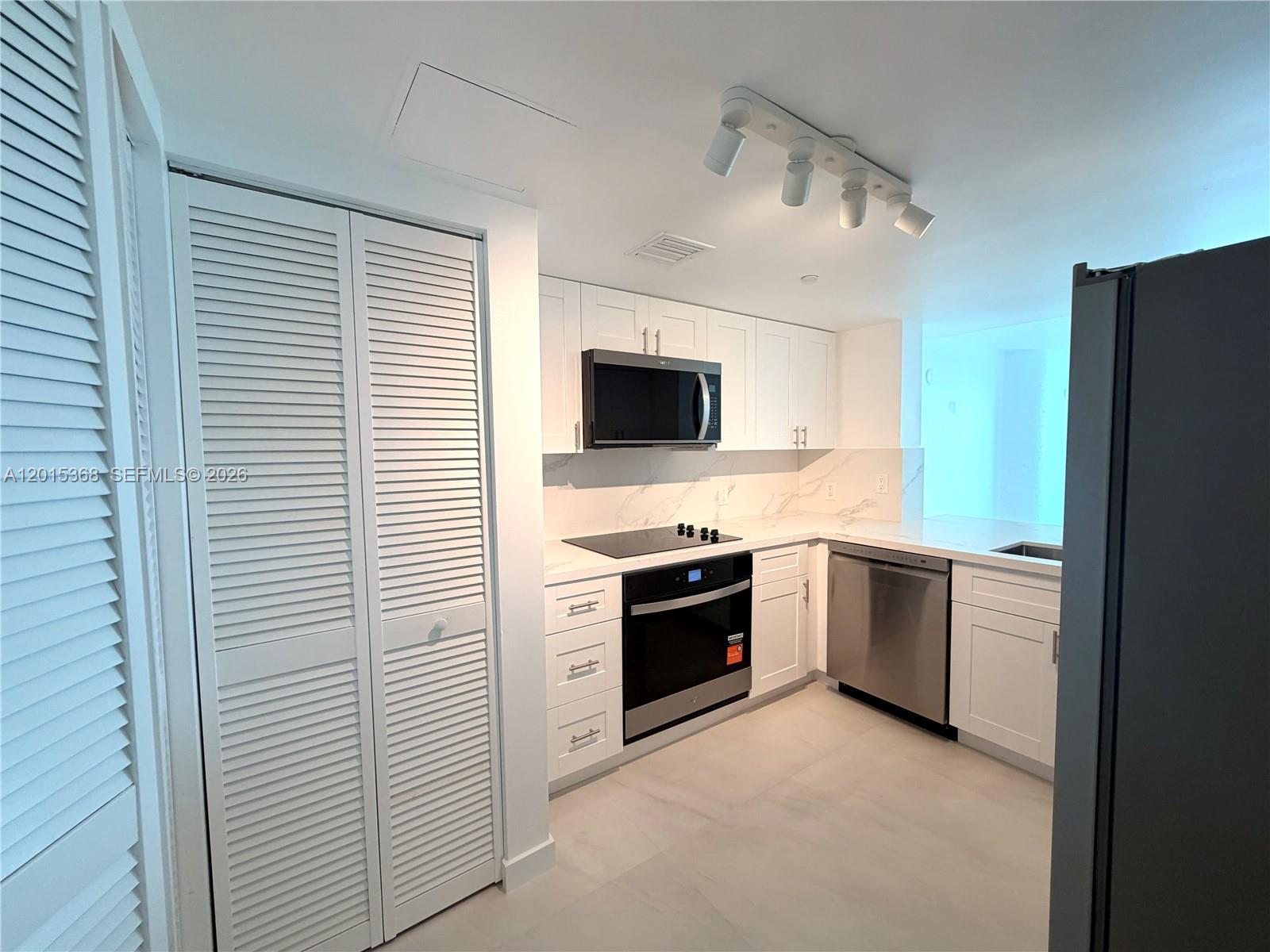 A modern kitchen features white cabinetry, stainless steel appliances, and marble-style countertops and backsplash — 2101 Brickell Ave # 2301, Miami FL 33129, MIAMI, FL