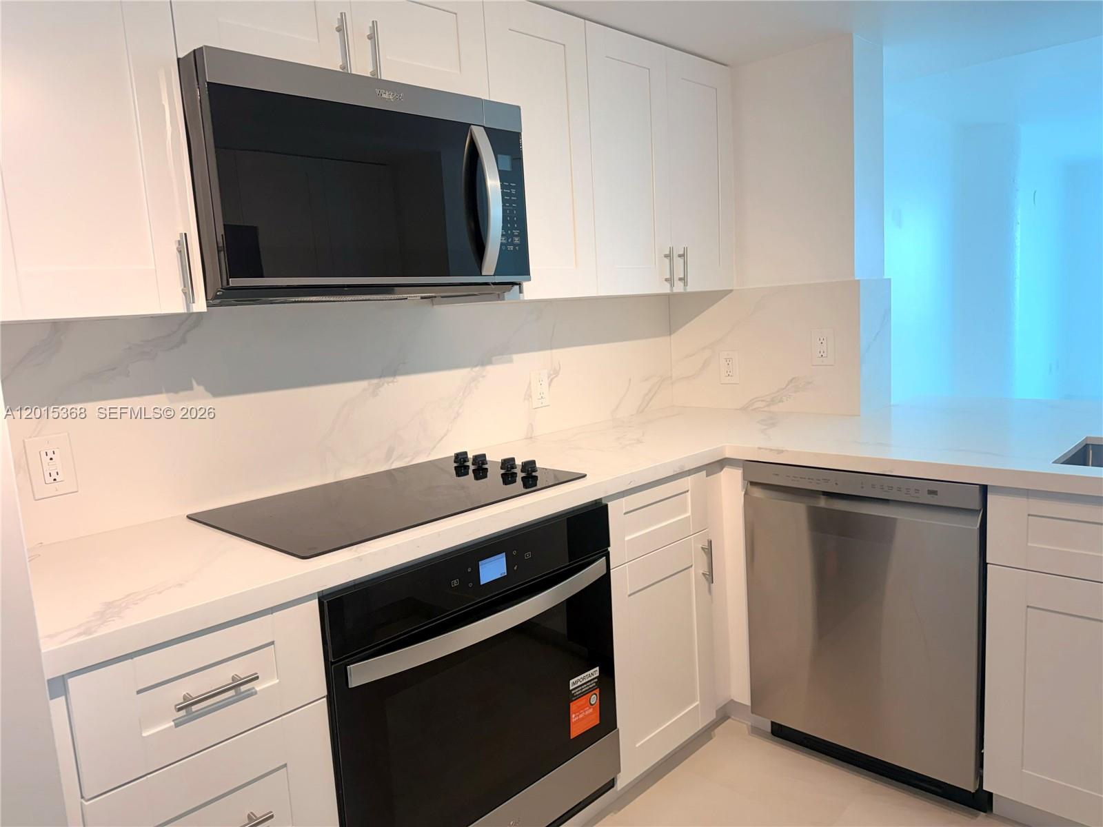 A modern kitchen features white cabinets, stainless steel appliances, and white marble-patterned countertops and backsplash — 2101 Brickell Ave # 2301, Miami FL 33129, MIAMI, FL