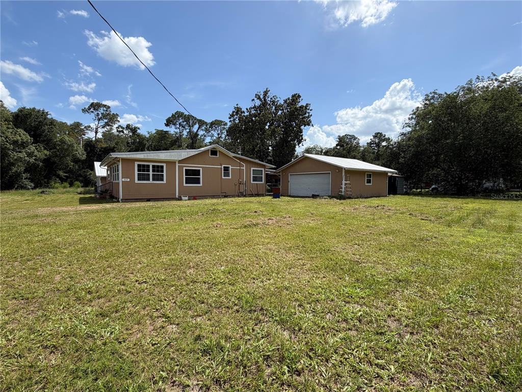 A tan house with a detached garage sits on a large, grassy lot — 9929 FACTORY AVENUE, HAMPTON, FL