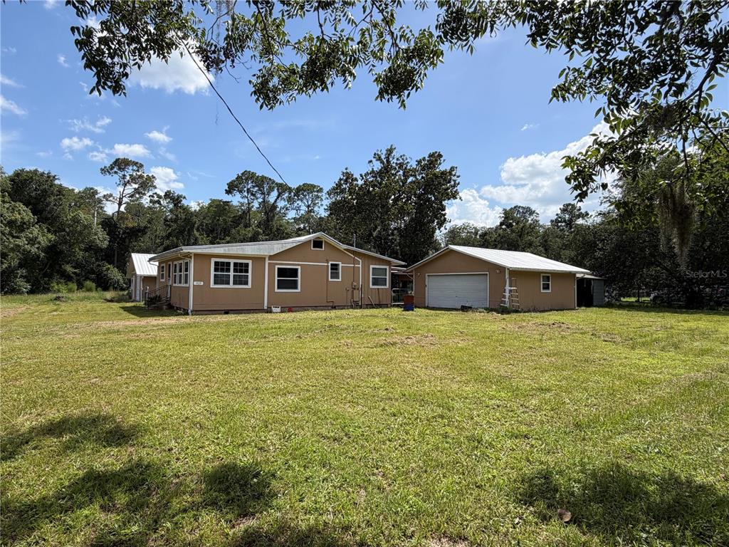 A tan single-story house with a detached garage sits on a large grassy lot — 9929 FACTORY AVENUE, HAMPTON, FL