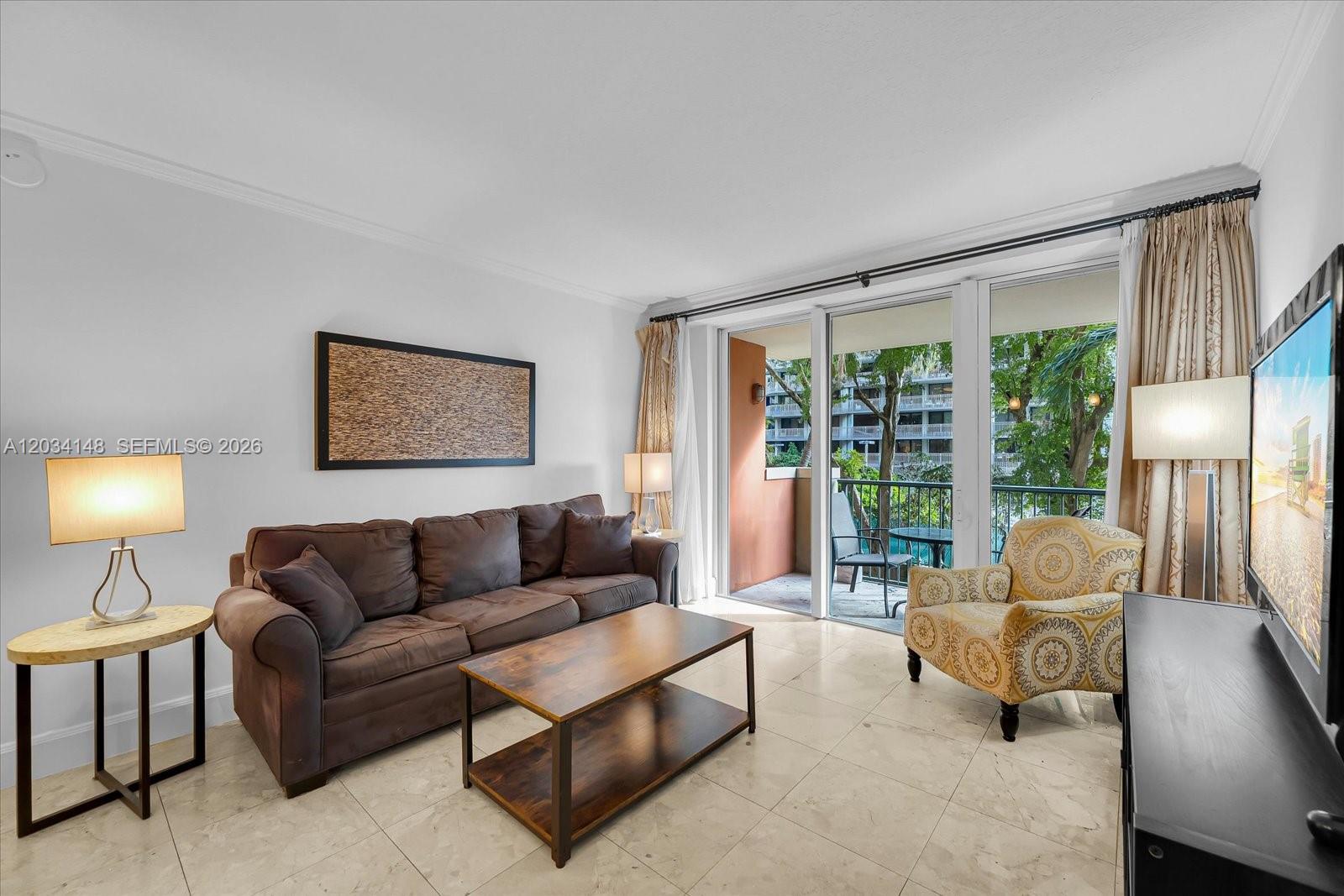 A living room features a brown sofa, patterned armchair, coffee table, and a balcony view — 2951 S Bayshore Dr # 307, Miami FL 33133, MIAMI, FL