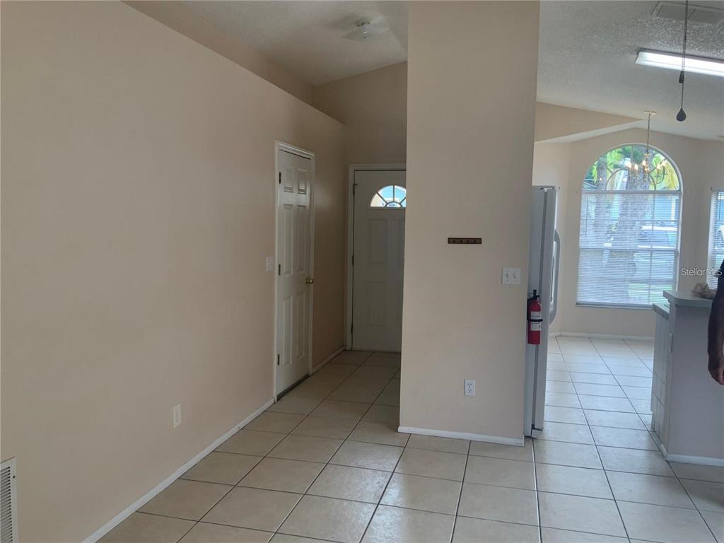 An interior view shows a tiled entryway with a front door, a closet, and a kitchen — 1705 CHATHAM CIRCLE, APOPKA, FL