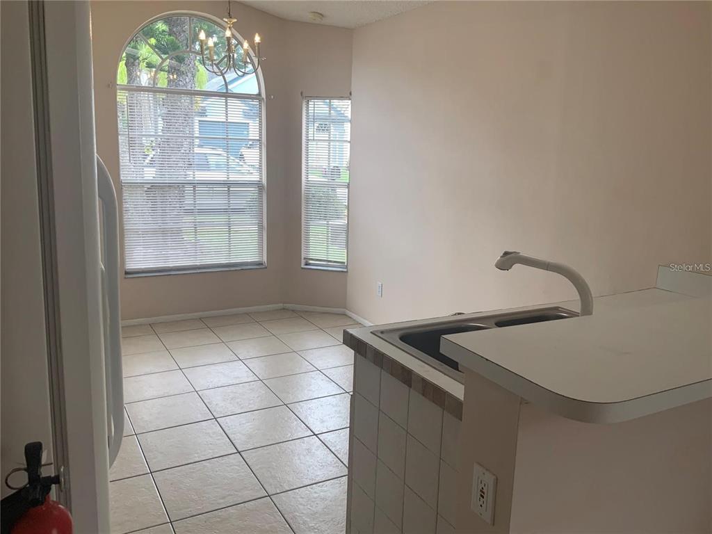 A kitchen and dining area with tile floors, a sink peninsula, and arched windows — 1705 CHATHAM CIRCLE, APOPKA, FL