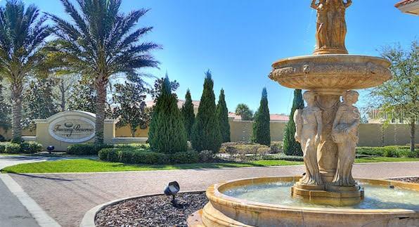 A stone fountain with statues stands in front of a Tuscany Preserve entrance sign — 1187 CHERVIL DRIVE, POINCIANA, FL