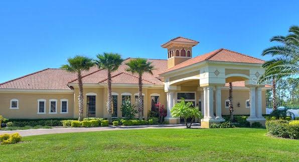 A tan, single-story building with a red tile roof and a covered entryway with columns — 1187 CHERVIL DRIVE, POINCIANA, FL