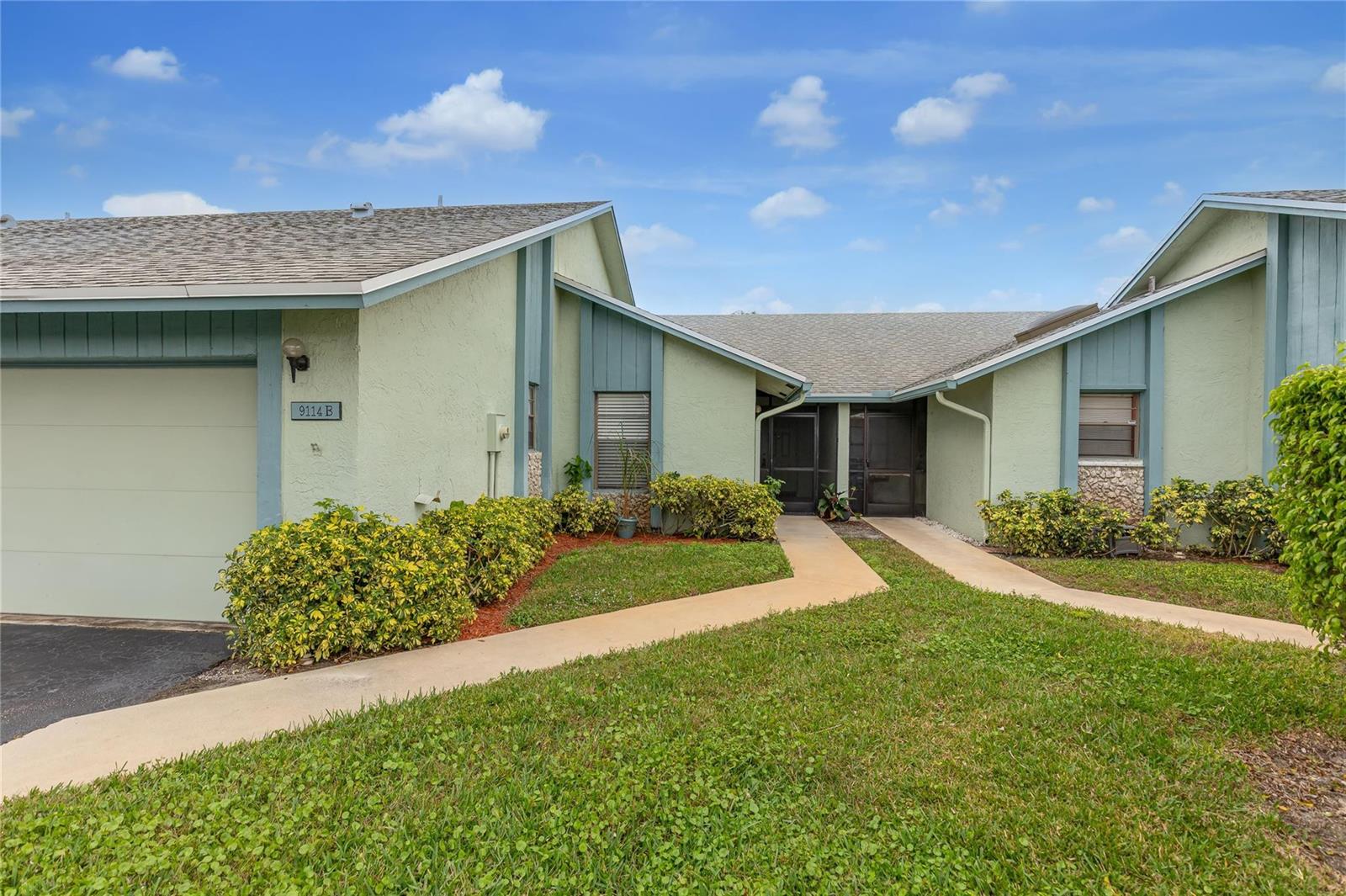 A light green single-story duplex with a garage, two entryways, and a shared concrete walkway — 9114 SW 20th Street # B, Boca Raton FL 33428, BOCA RATON, FL