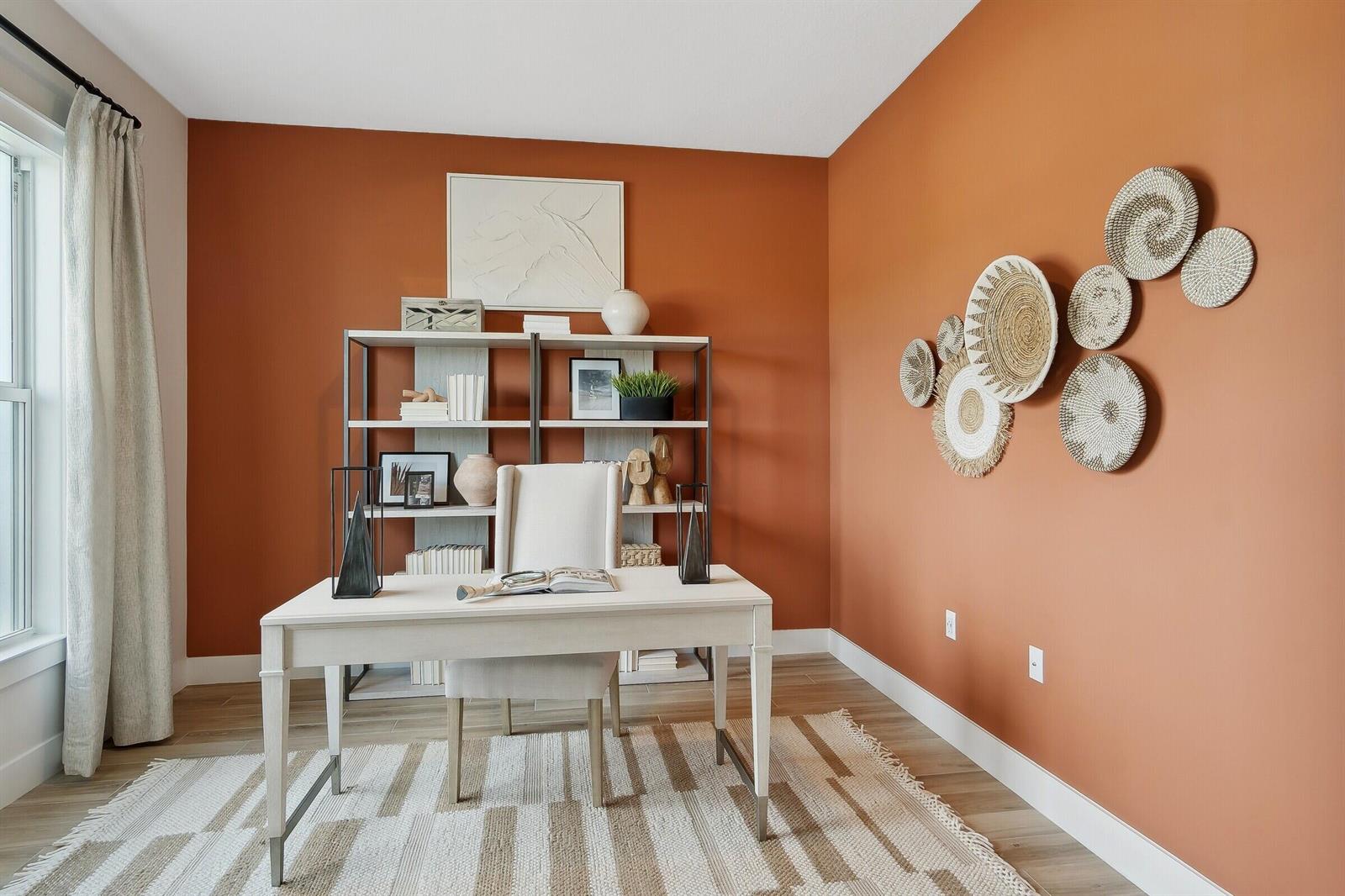 A home office features a white desk, a bookshelf, and woven wall decor on terracotta walls — 6806 SE Lost Pine Drive, Stuart FL 34997, STUART, FL