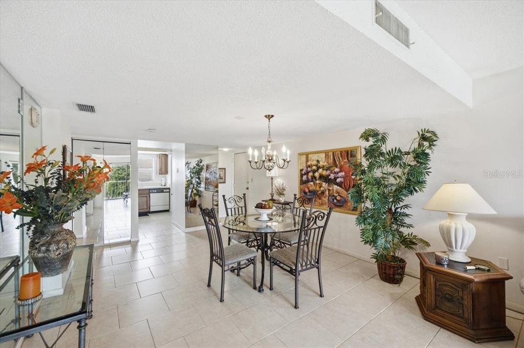 A living room features tile flooring, a large wooden entertainment center, and a sliding glass door — 7050 SUNSET DRIVE S UNIT 216, SOUTH PASADENA, FL