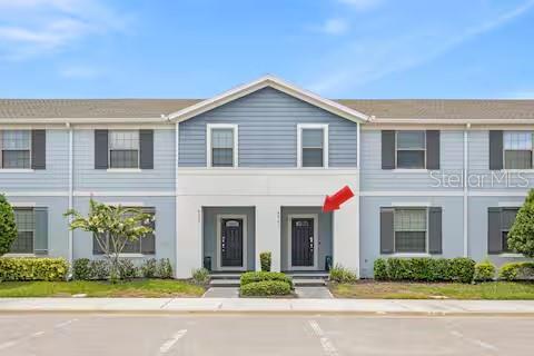 The exterior of a two-story townhouse building features blue siding and two front entry doors — 8923 SYDNEY AVENUE, KISSIMMEE, FL