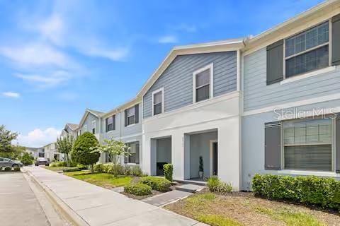 A multi-story residential building with blue siding and a concrete sidewalk in front — 8923 SYDNEY AVENUE, KISSIMMEE, FL
