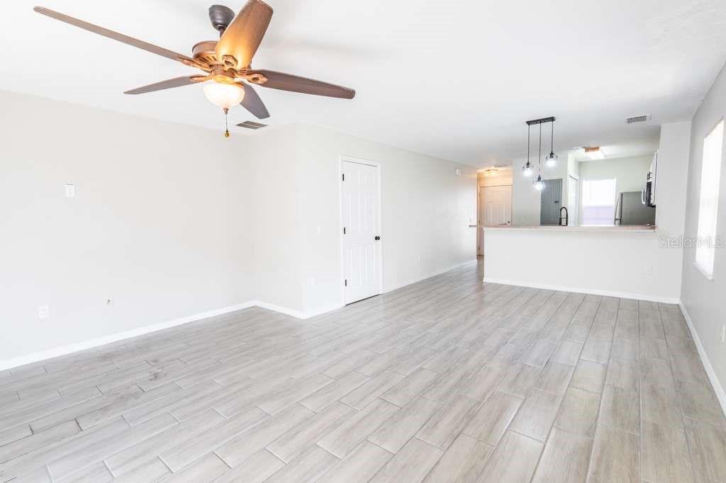 A living room with light gray tile flooring, a ceiling fan, and an open kitchen — 141 JONES LANE UNIT A, KISSIMMEE, FL