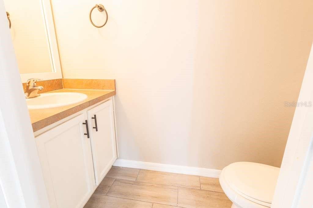 A small bathroom features a white vanity, a sink, and a toilet on tiled flooring — 141 JONES LANE UNIT A, KISSIMMEE, FL