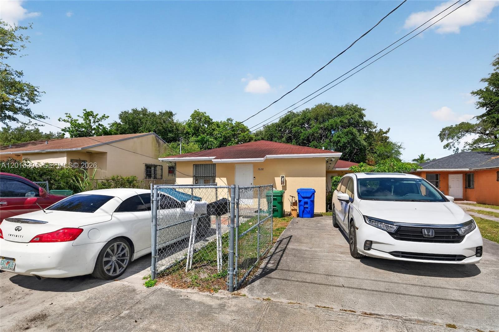 A single-story house with a concrete driveway, a chain-link fence, and two parked cars — 7628 NW 2nd Ct, Miami FL 33150, MIAMI, FL