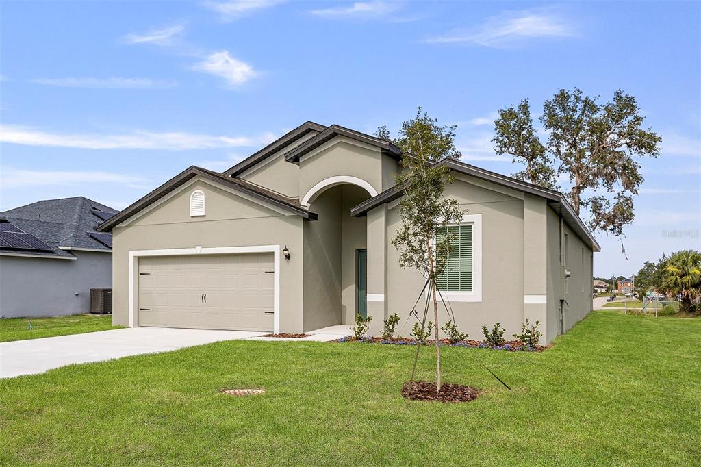 A single-story house with a beige stucco exterior, a two-car garage, and a front lawn — 247 BIG SIOUX DRIVE, POINCIANA, FL