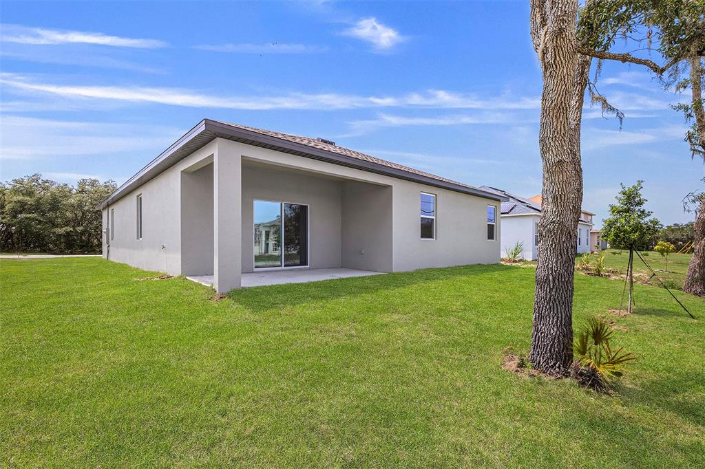 The rear exterior of a single-story house features a covered patio and a grassy yard — 247 BIG SIOUX DRIVE, POINCIANA, FL