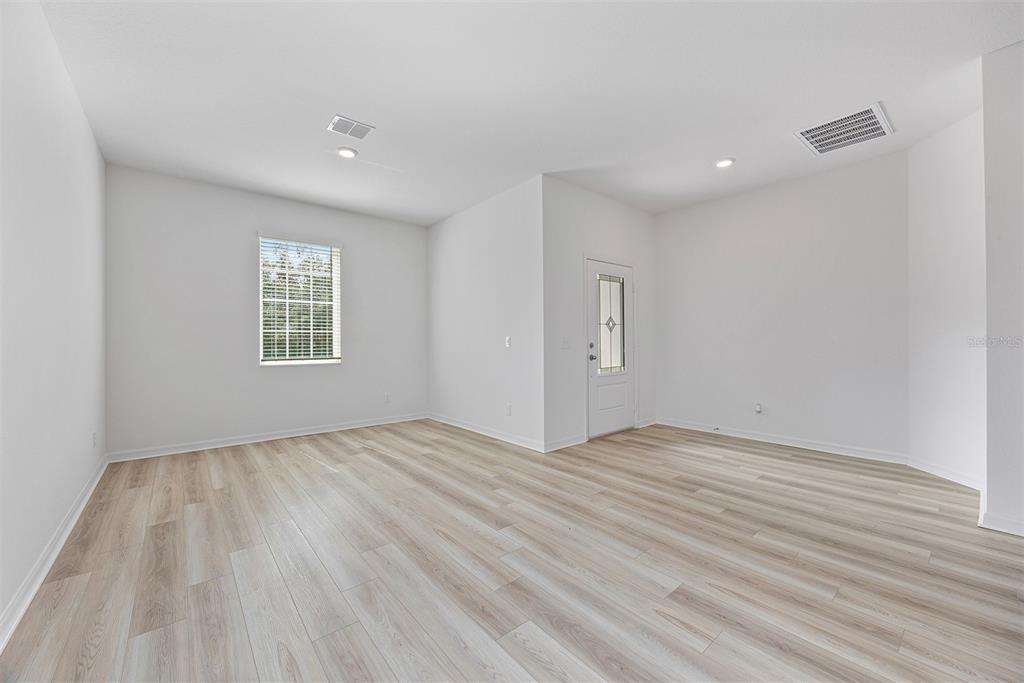 An empty room with white walls, light wood-look flooring, a window, and a glass-paneled door — 247 BIG SIOUX DRIVE, POINCIANA, FL